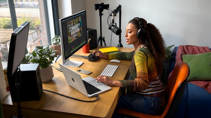 Una mujer trabajando en su escritorio y mostrando que es Macbook.