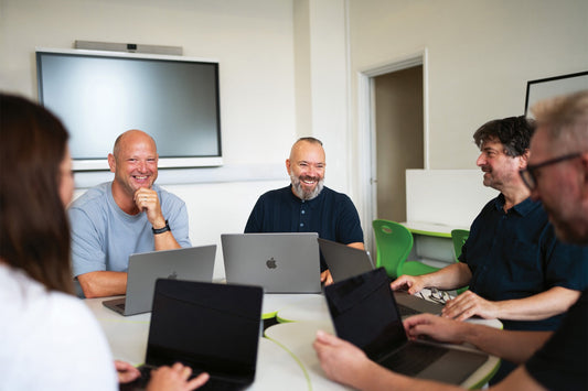 Grupo de personas trabajando en una computadora de escritorio, mostrando su uso como computadores para diseño gráfico en un entorno colaborativo.